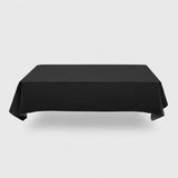 A plain black tablecloth drapes over a rectangular table with folded corners against a light grey background.