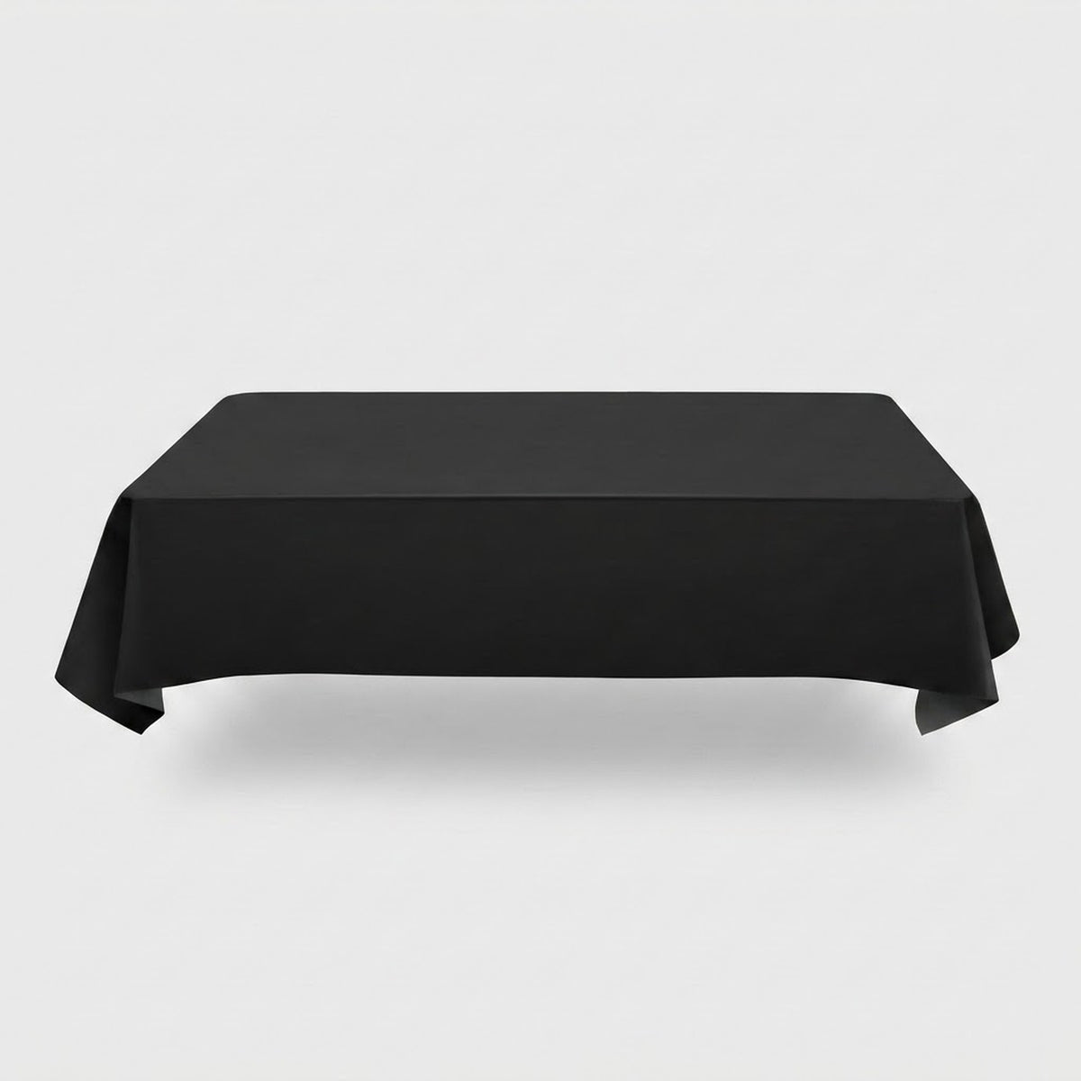 A plain black tablecloth drapes over a rectangular table with folded corners against a light grey background.