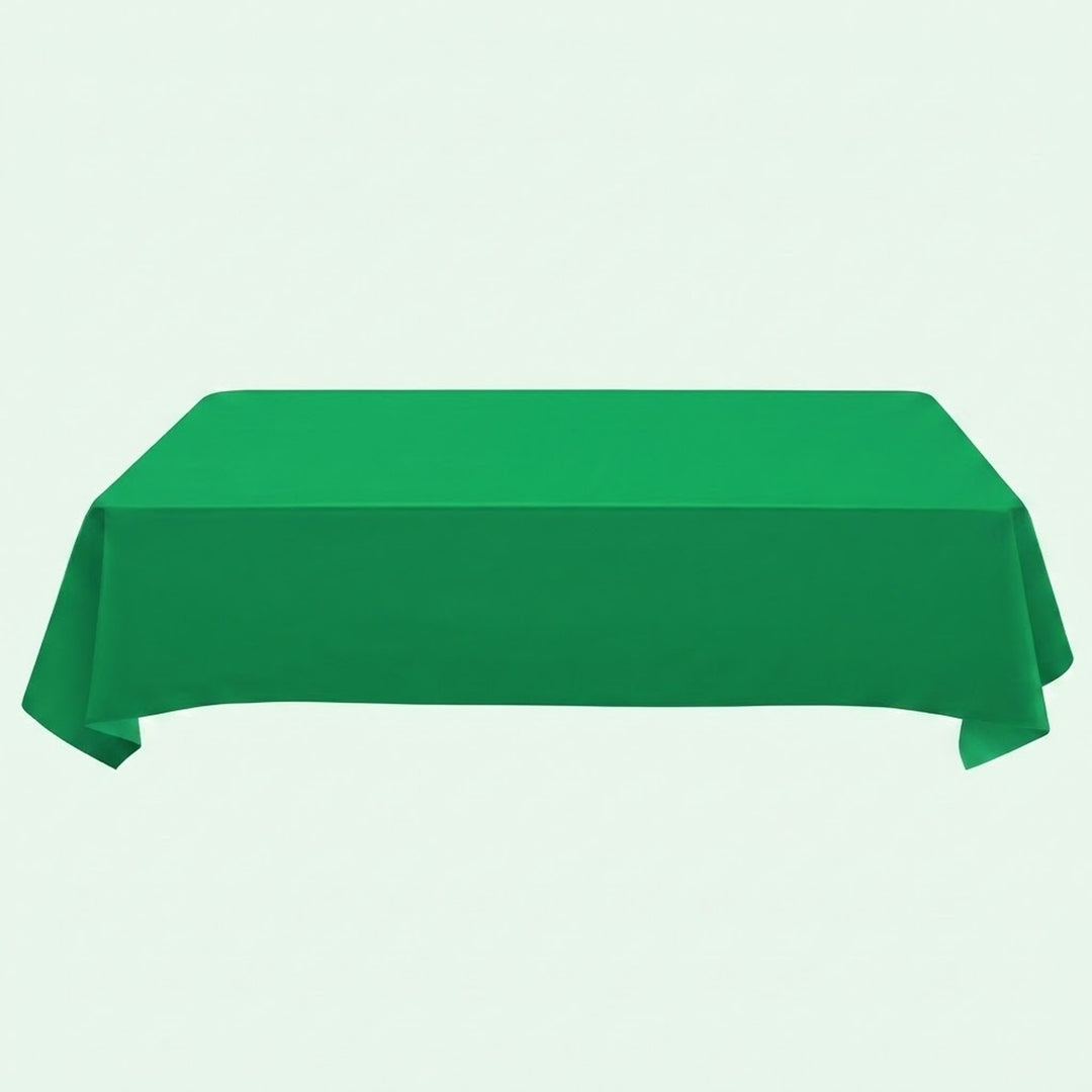 A green tablecloth drapes over a rectangular table with hanging side corners against a pale mint background.
