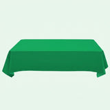 A green tablecloth drapes over a rectangular table with hanging side corners against a pale mint background.