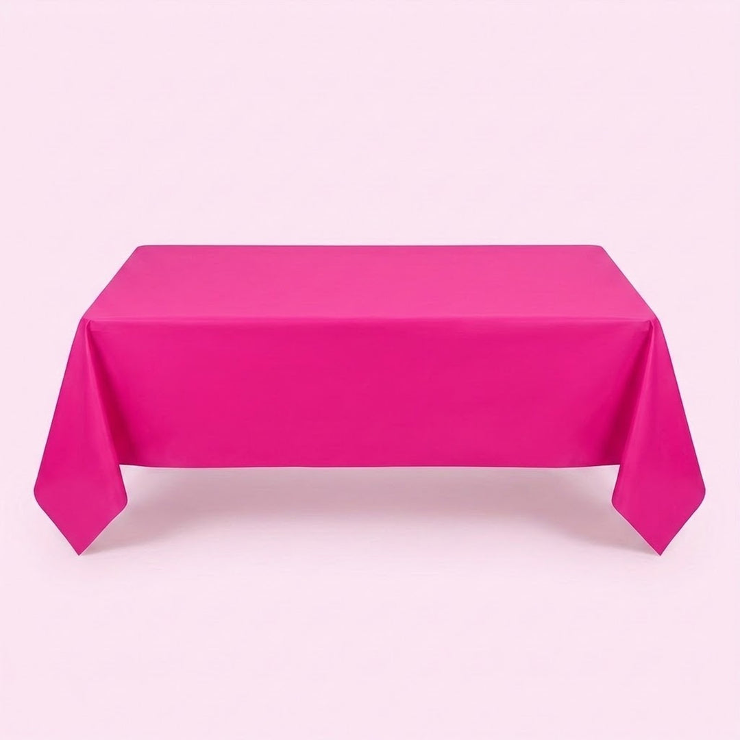 A hot pink tablecloth covers a rectangular table with long pointed corner folds against a pale pink background.