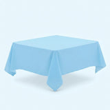 A light blue tablecloth covers a table viewed diagonally, with a pointed front corner against a pale blue background.