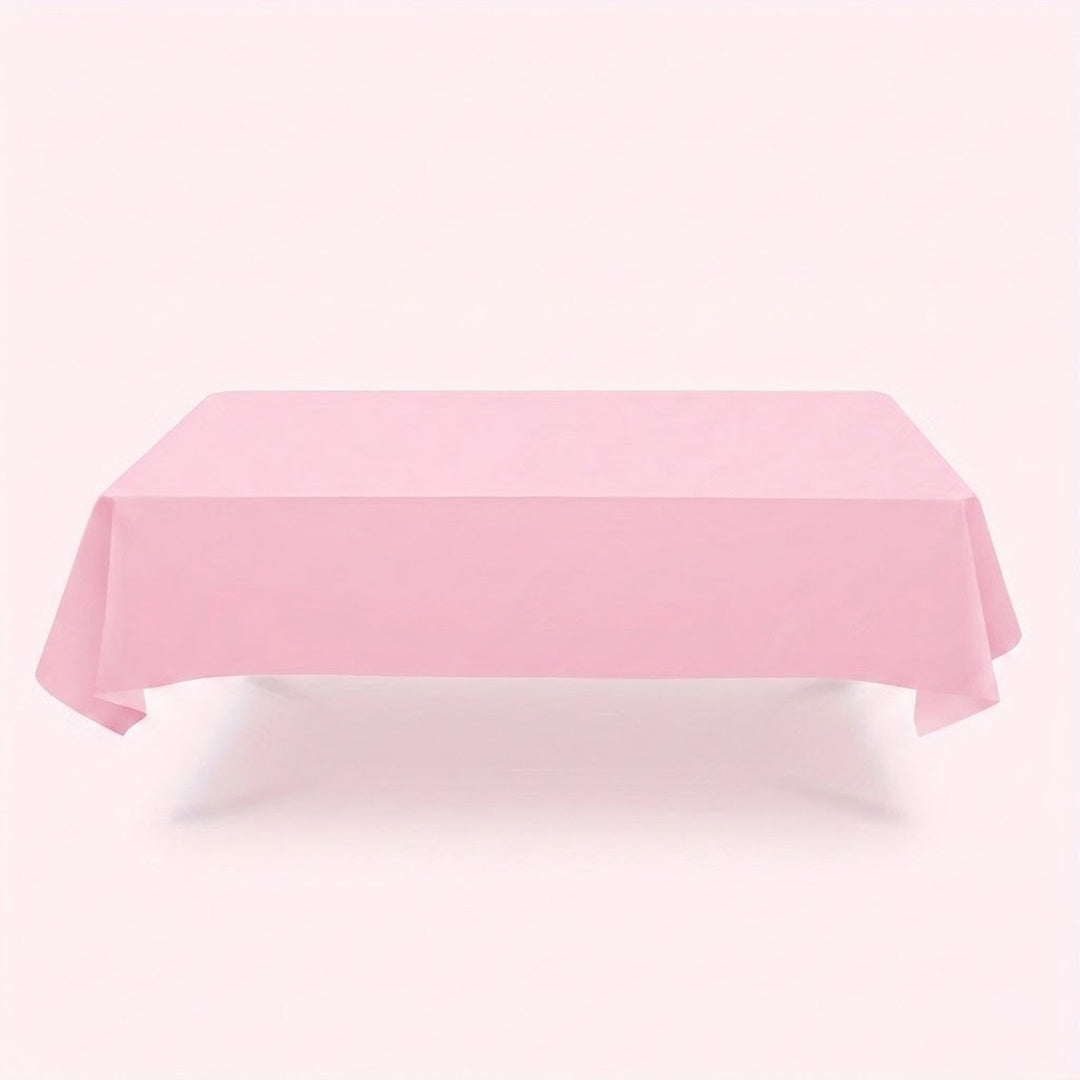 A light pink tablecloth drapes over a rectangular table with hanging corners against a pale pink background.