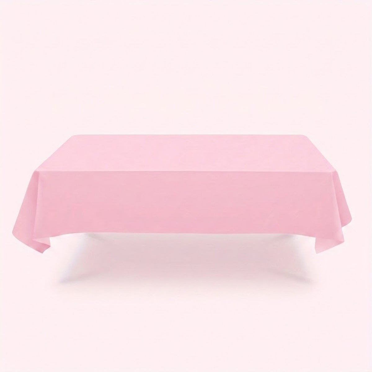 A light pink tablecloth drapes over a rectangular table with hanging corners against a pale pink background.