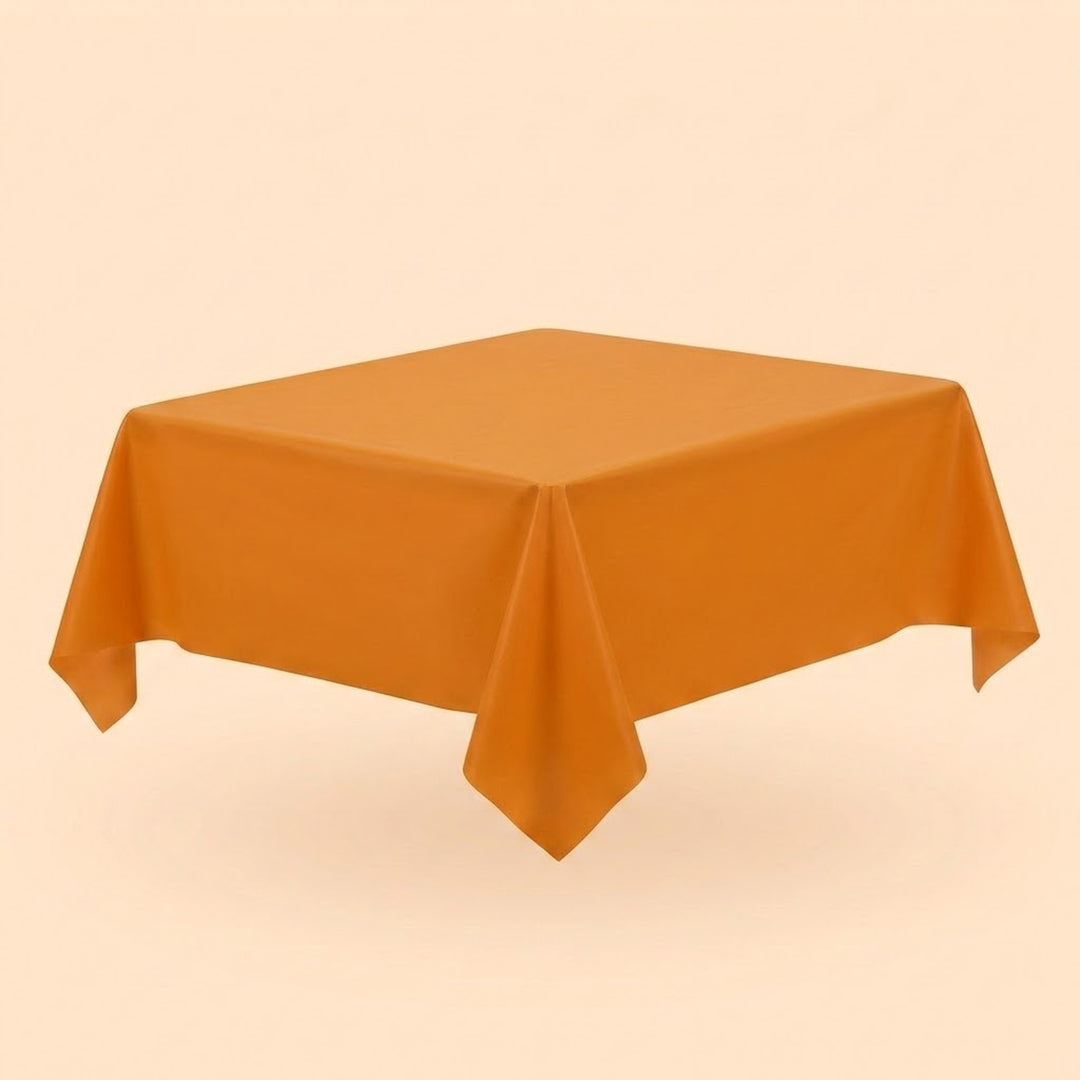An orange tablecloth covers a table viewed diagonally, with pointed hanging corners against a pale peach background.