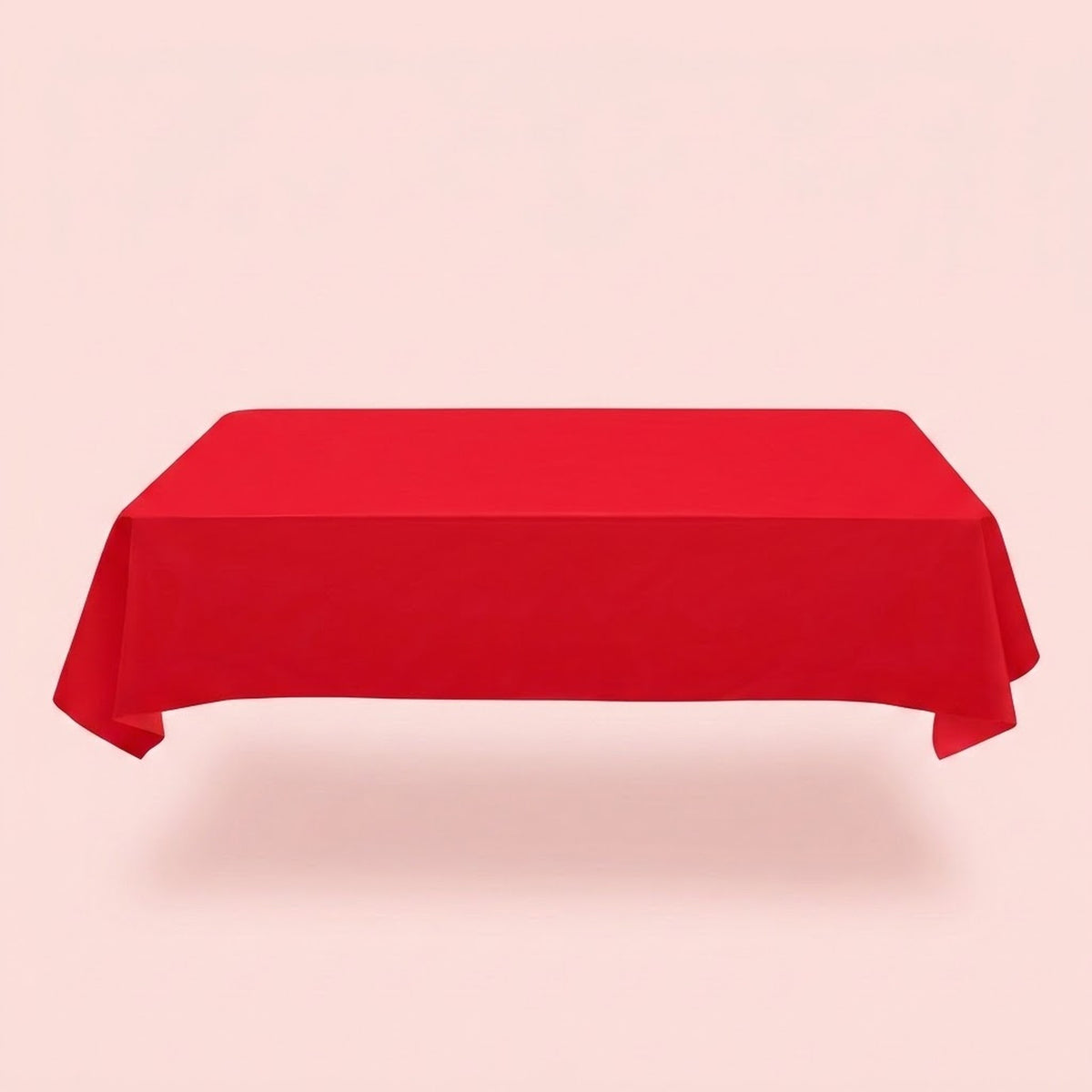 A plain red tablecloth covers a rectangular table with draped sides and folded corners against a pale pink background.