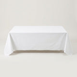 A white tablecloth drapes over a rectangular table against a light beige background.