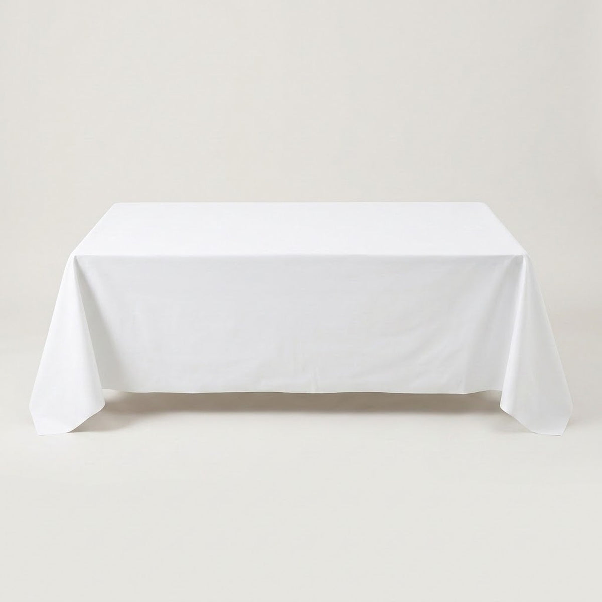 A white tablecloth drapes over a rectangular table against a light beige background.