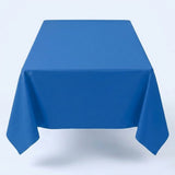 A blue tablecloth covers a rectangular table with long corners hanging down against a pale background.