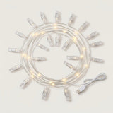 Warm white photo clip lighting with clear clips and silver-colored wire lies coiled beside a white USB cable on a white background.