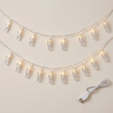 Photo clip lighting with clear plastic clips glows warm white in two curved rows beside a white USB cable on a cream background.