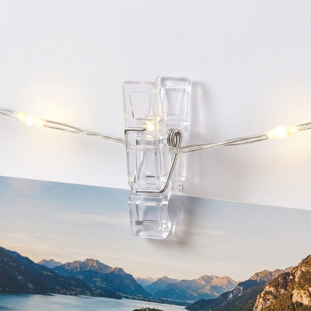 Warm white photo clip lighting features a clear plastic clip holding a mountain photograph against a white background.
