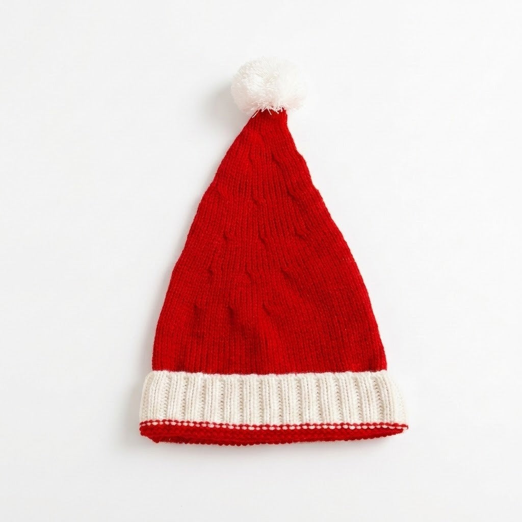 A red knit Santa hat with a white ribbed cuff and a fluffy white pom-pom on top, photographed against a plain white background.