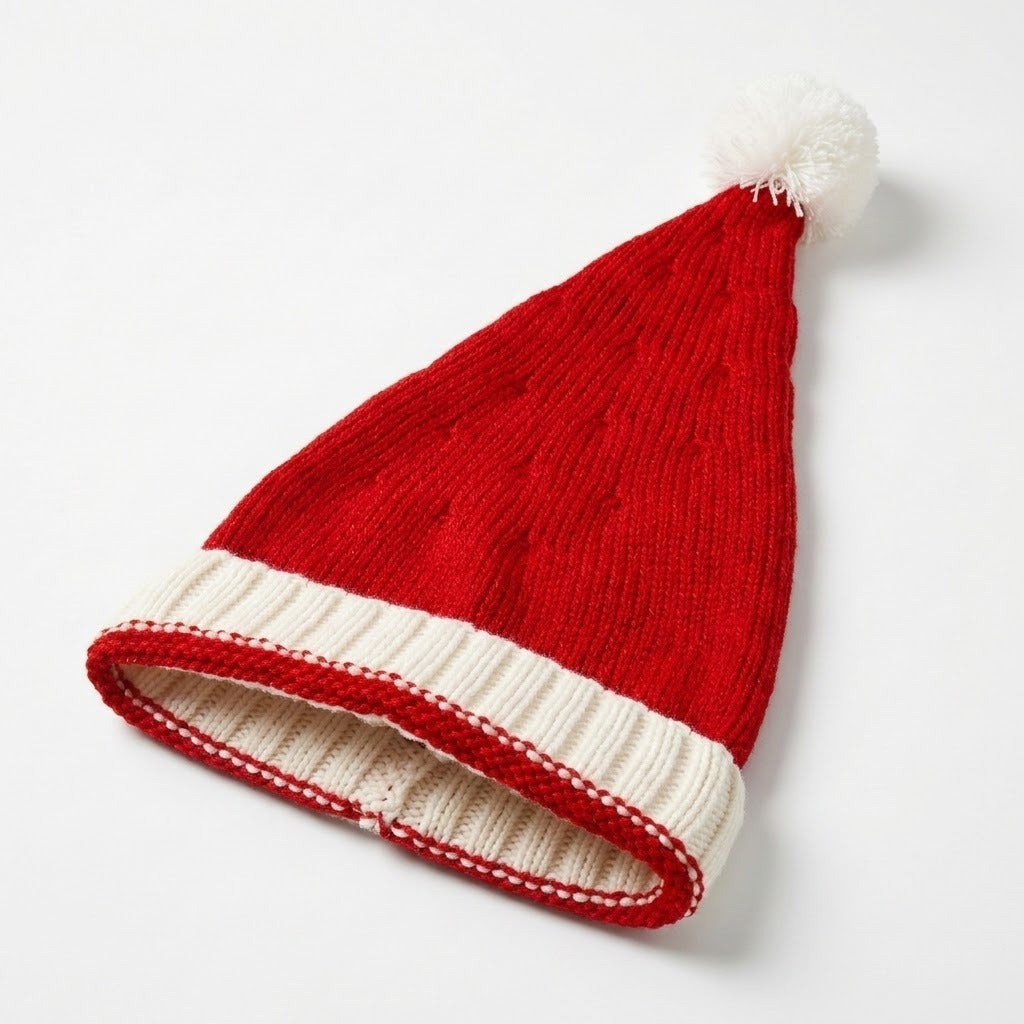 A red knitted Santa hat with a white ribbed cuff and fluffy white pompom lies diagonally on a white background.