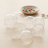 Clear plastic fillable ornaments lie open in halves on pale wood beside red, green, and beige craft shapes.