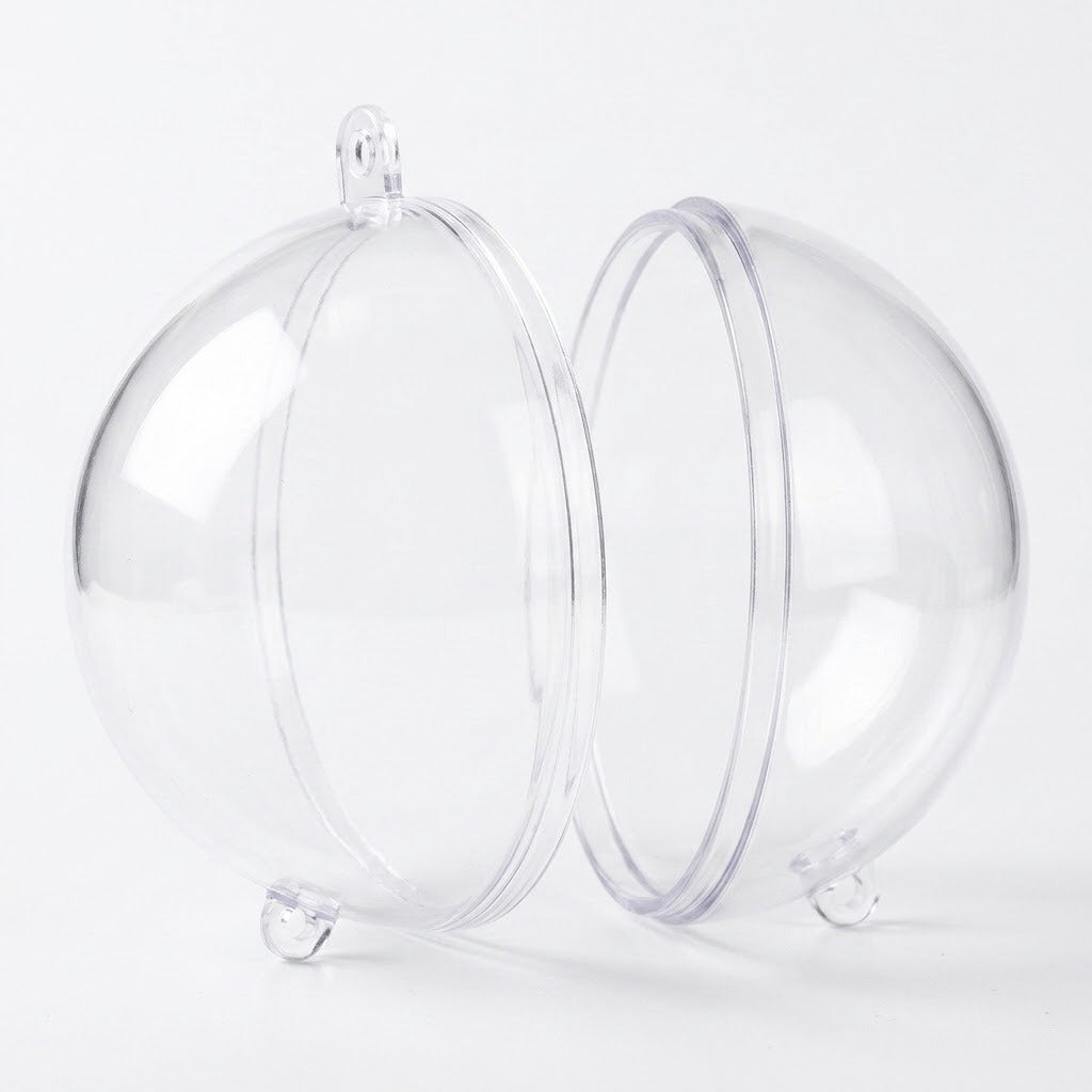 A clear plastic fillable ornament separates into two halves, displaying circular joining rims and hanging tabs against white.