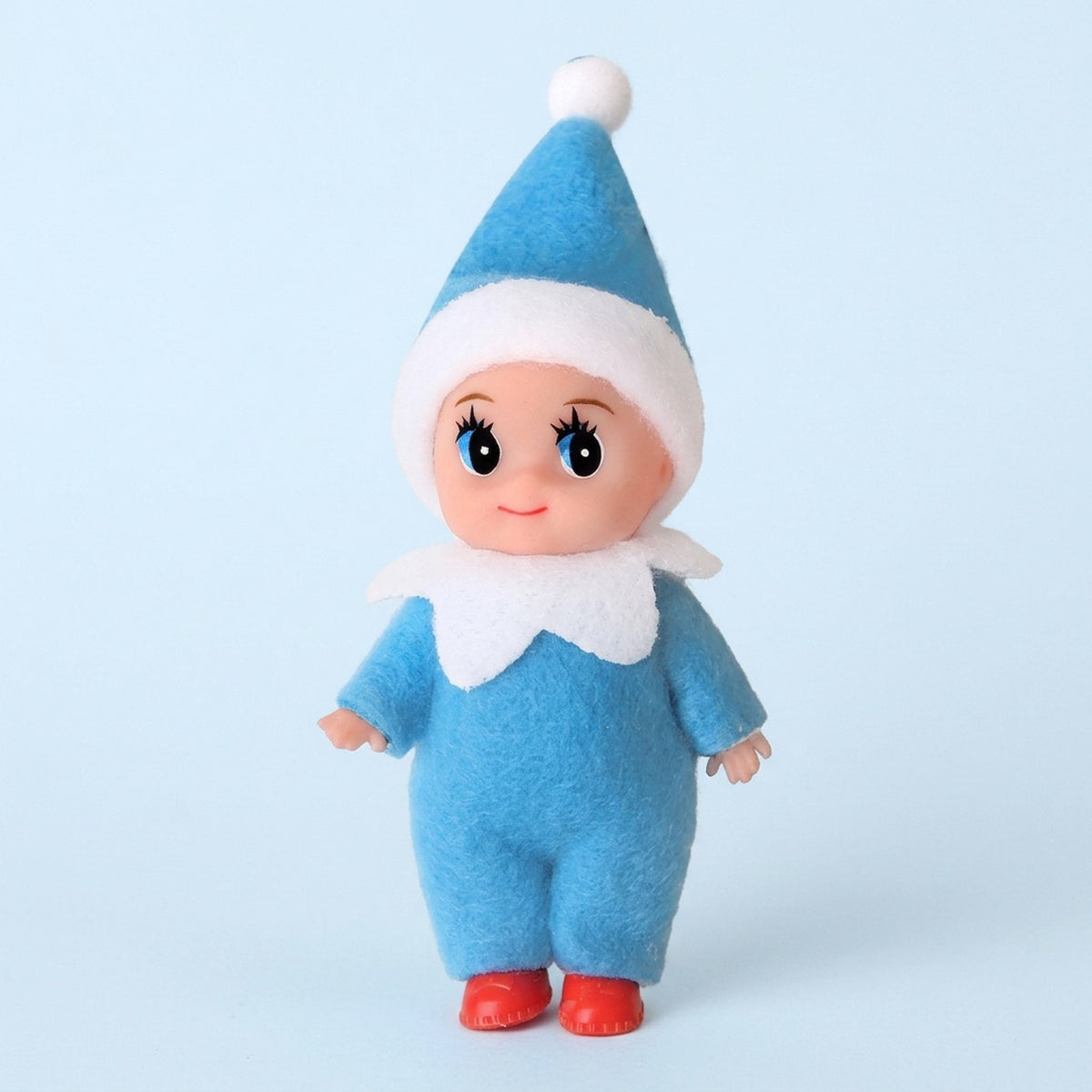 Elf doll wears a blue fabric outfit, white-trimmed pointed hat, white collar, and red shoes against a pale blue background.