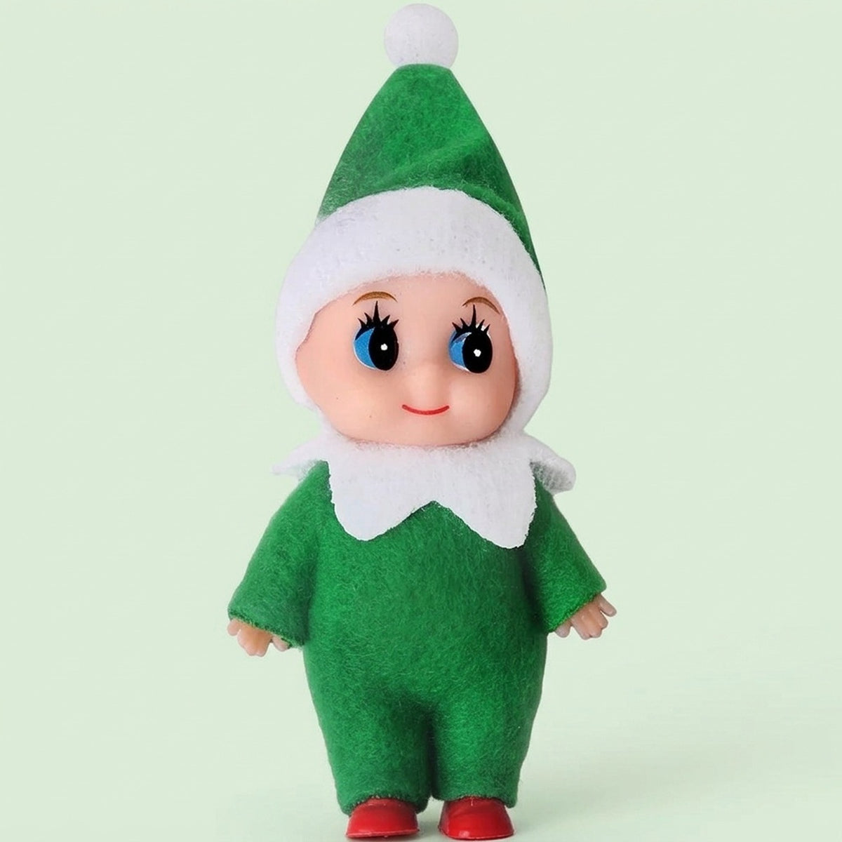 Elf doll wears a green fabric outfit, white-trimmed pointed hat, white collar, and red shoes against a pale green background.