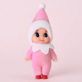 Elf doll wears a pink fabric outfit, white-trimmed pointed hat, white collar, and red shoes against a pale pink background.
