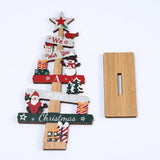 Wooden tabletop Christmas decoration with red, green and white details lies beside its separate slotted wooden base on a white background.
