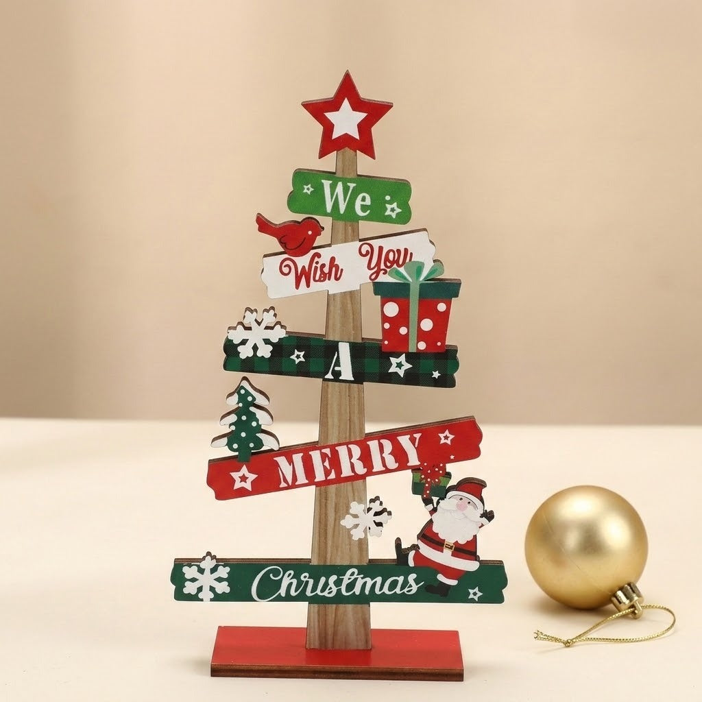 Wooden tabletop Christmas decoration with red and green signs stands beside a gold bauble on a cream surface against a beige background.