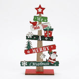 Wooden tabletop Christmas decoration with red, green and white message signs, a star topper, Santa and snowflakes against a white background.