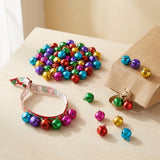 Multicoloured jingle bells decorate a ribbon loop and brown paper bag, with loose bells scattered across a light wooden tabletop.