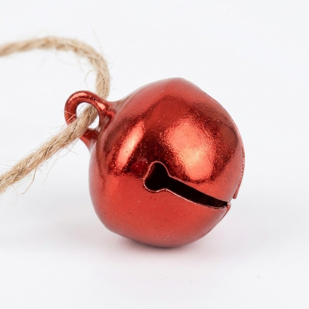 A shiny red jingle bell with a curved opening has natural twine threaded through its hanging loop against a white background.