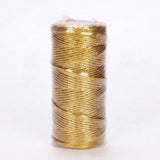 A spool of metallic gold craft cord stands upright in clear plastic wrapping against a plain white background.