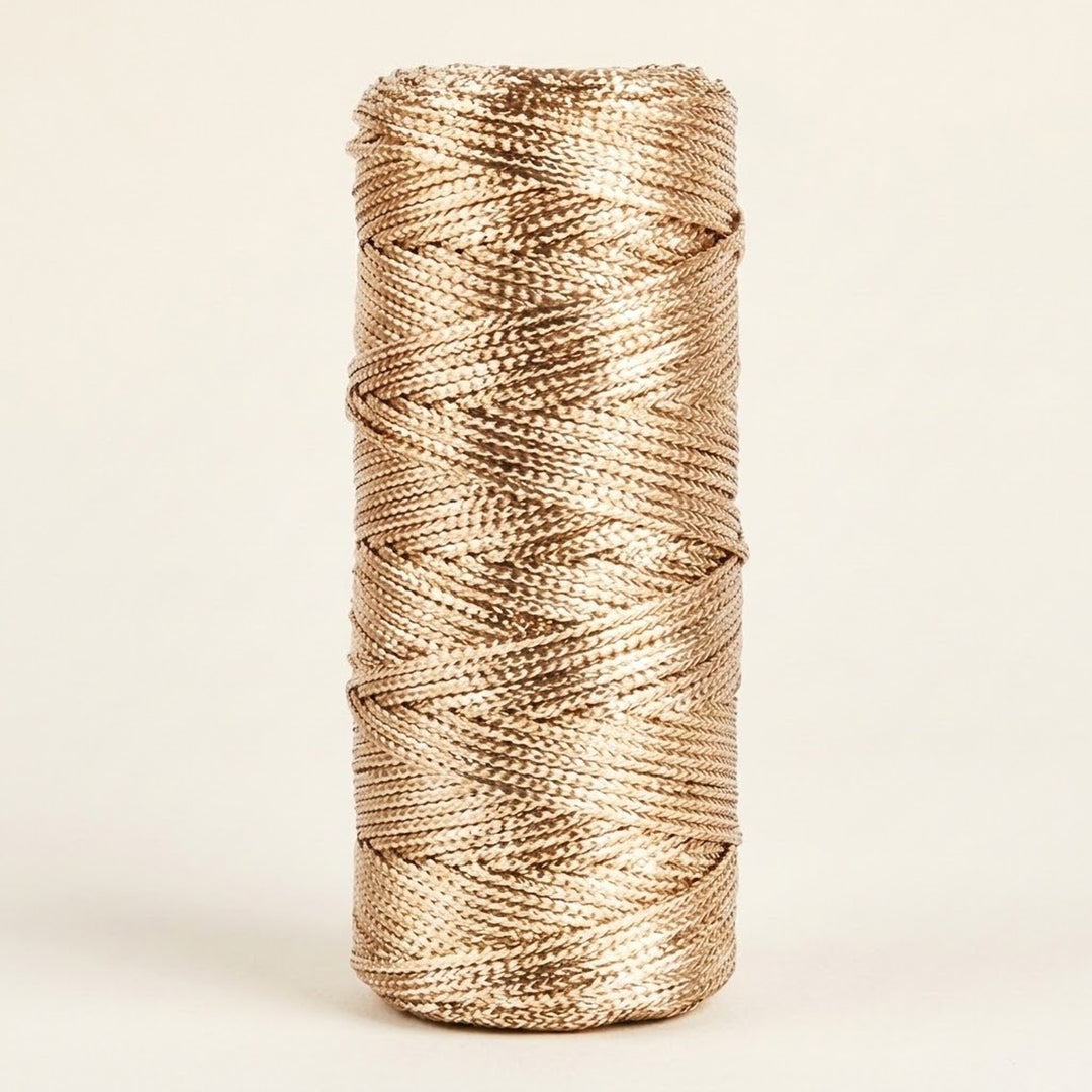 Champagne gold craft cord with a metallic sheen is wound on an upright spool against a cream background.