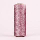 Shiny light pink twisted craft cord is wound around an upright cardboard spool against a pale pink background.