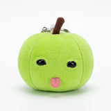 Green plush apple keychain with black eyes, pink tongue, brown stem, and a partially visible silver keyring against a white background.