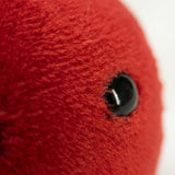 Close-up of a red plush apple keychain showing fuzzy fabric, a curved seam, and a glossy black eye against white.