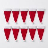Ten red Santa hat cutlery holders with white cuffs and pompoms lie in two rows of five on a white background.
