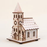 A pale wooden Christmas house with a pointed tower, starburst window cutouts, and fir trees stands against a cream background.