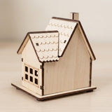 A pale wooden Christmas house viewed from behind shows a plain back wall, chimney, and scalloped roof against a cream background.