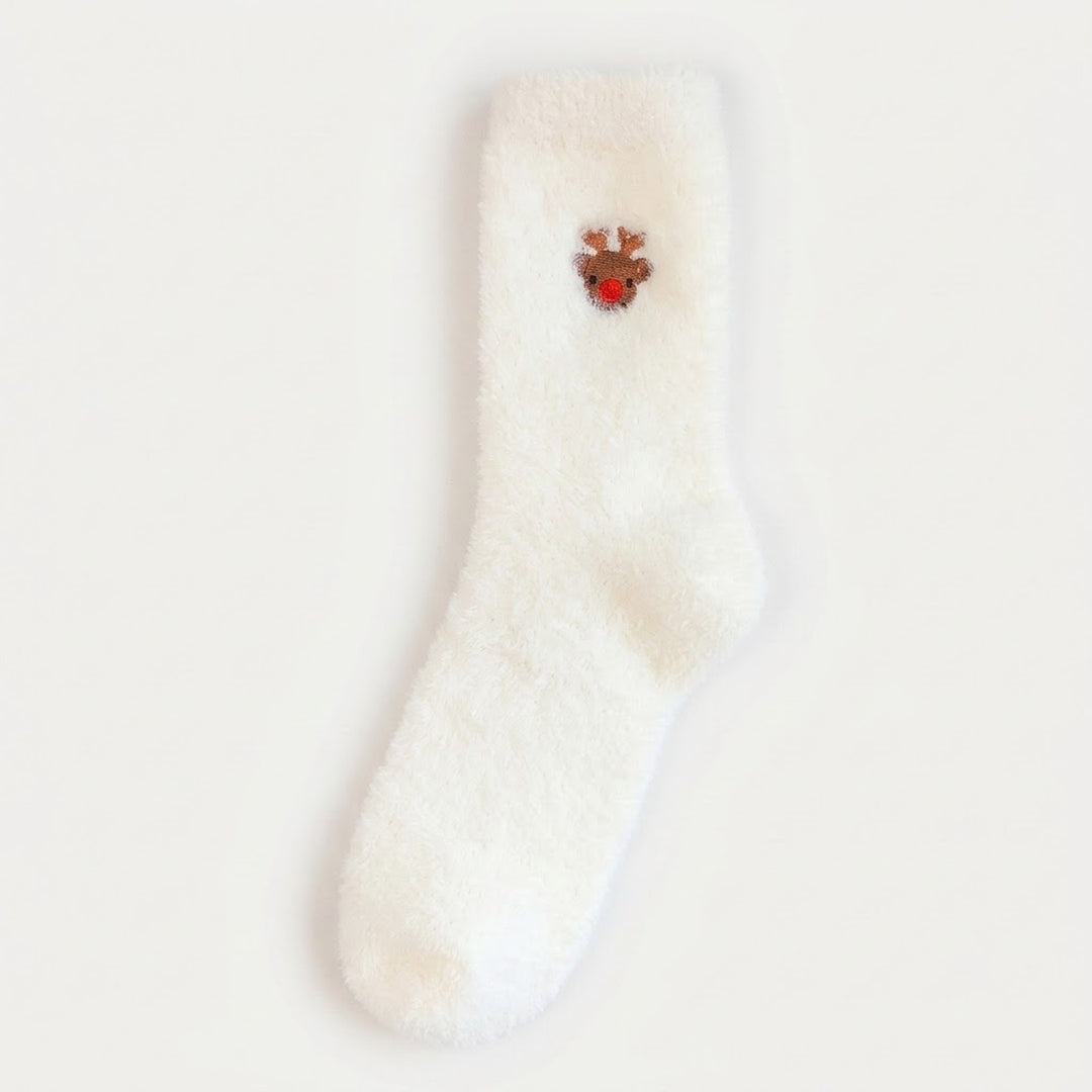 A fluffy white sock with a brown reindeer face and red nose lies flat on a pale background.