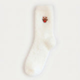 A fluffy white sock with a brown reindeer face and red nose lies flat on a pale background.