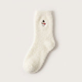 A fluffy white sock with a snowman wearing a black hat and red scarf lies flat on a pale background.