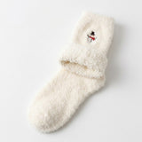 A single fluffy cream-colored sock with a small embroidered snowman detail on the cuff, displayed on a clean white background.