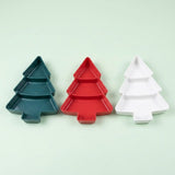 Green, red, and white Christmas tree serving trays, each with three compartments, stand side by side against a pale green background.