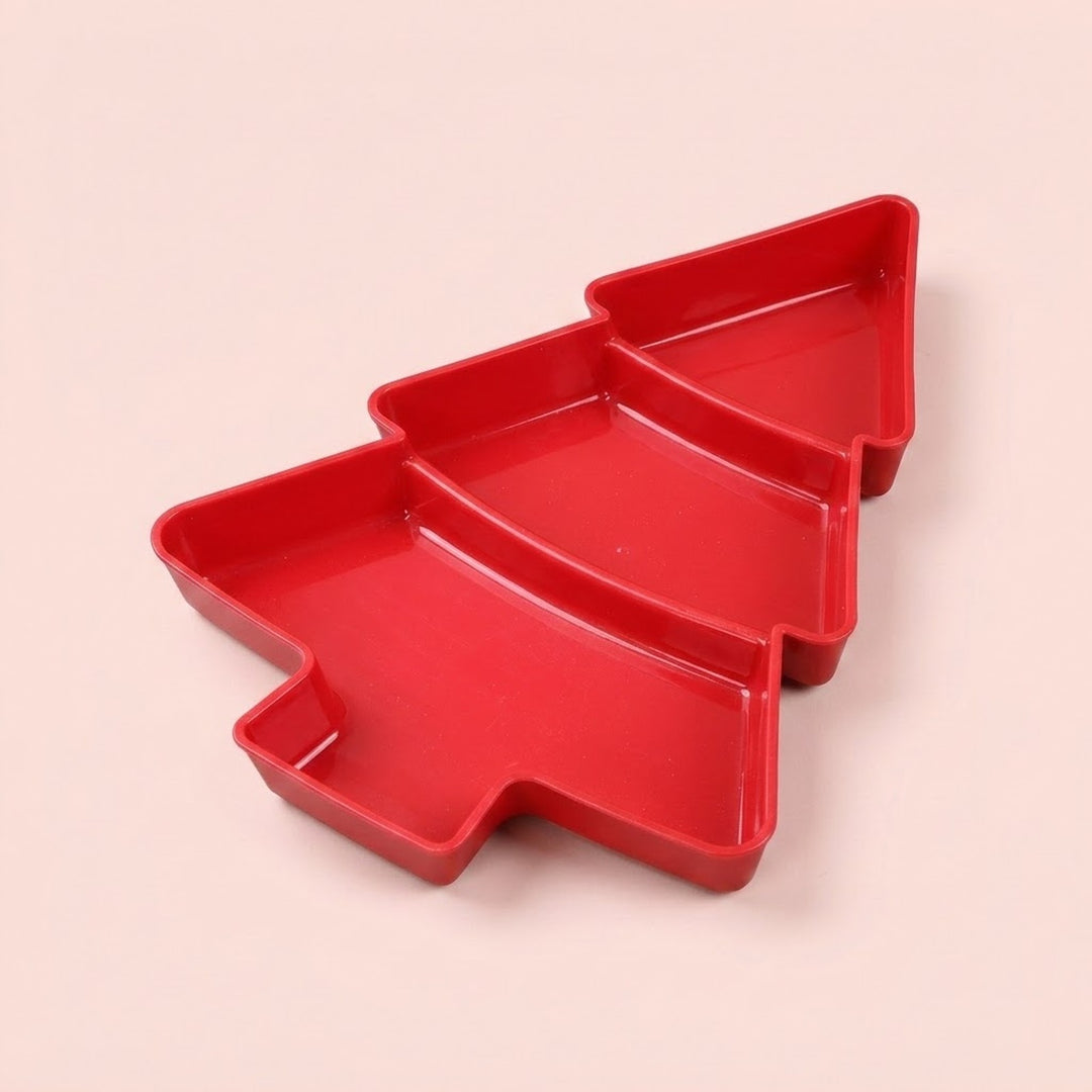 Red Christmas tree serving tray with three divided compartments sits diagonally against a pale pink background.