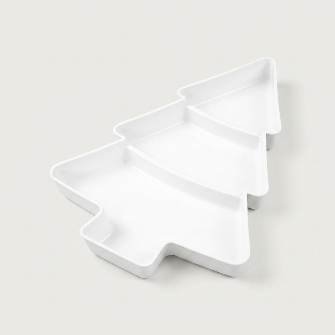 White Christmas tree serving tray with three divided compartments sits diagonally against an off-white background.