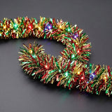 A red, green, and gold tinsel lighted garland curves across a gray surface with glowing red, green, purple, and yellow bulbs.