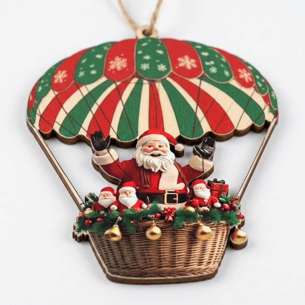 A flat timber Christmas ornament depicting Santa beneath a red, green, and cream parachute rests on white, showing its brown edge.