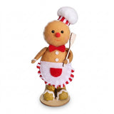 Tan plush gingerbread sitter wears a white chef hat and white apron with red accents, holding a spatula against a white background.