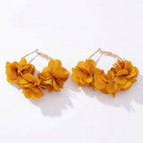 A pair of gold hoop earrings adorned with clusters of layered yellow fabric flowers, displayed on a clean white background.