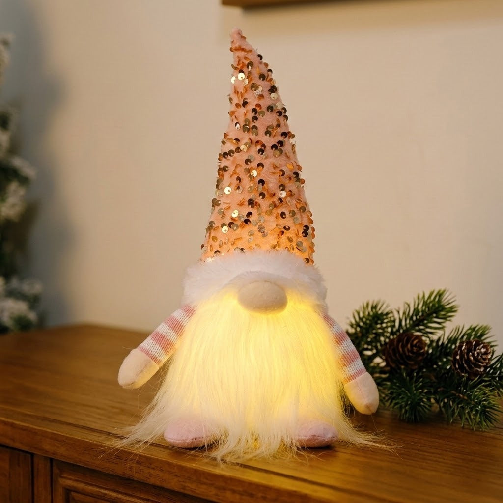 A Christmas gnome with a pink sequined hat and illuminated white beard stands on a wooden sideboard beside evergreen branches and pinecones.
