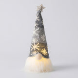 Glowing Christmas gnome wears a gray knitted snowflake hat with a pale star above its white beard against a light gray background.