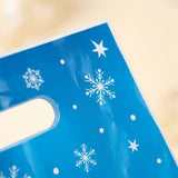 Blue Christmas gift bag close-up shows a glossy surface, white snowflakes, stars, dots, and an oval handle against a beige background.